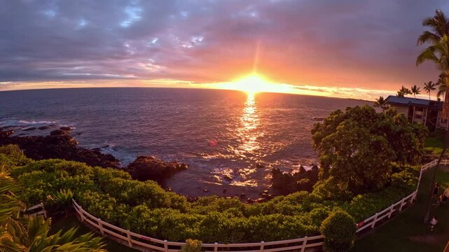 30 Seconds Sunset Time Lapse, Hawaii. Kona, Big Island. Waves Crashing on a Rocky Shoreline while People Moving Around in a Fenced Backyard Taking Pictures. Hotel and Palm Trees in The Landscape. 4K