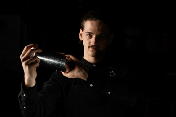 Bartender expertly shakes mix in silhouette against a black backdrop.