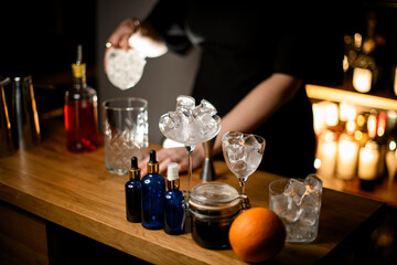 On the bar are blue bottles with pipettes, an orange and glasses of various sizes filled with ice
