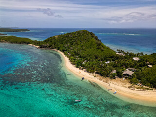Aerial view of tropical island beach with shallow turquoise water and corals reefs seen from above. Boats and resort perched on Mantaray Island in Fiji's famous touristic Yasawa region.  © James