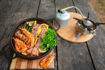 Baked salmon steaks with herbs and asparagus in a black cast iron skillet.