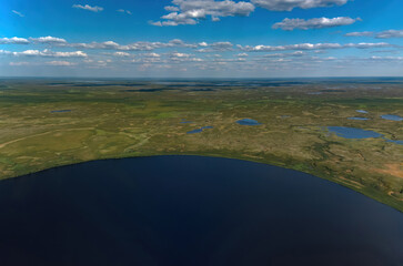 Arctic tundra in summer from an altitude of 2000 meters. Cloudy sky. Variety of colors and landscapes. The vastness of pristine nature. Shadow from the clouds