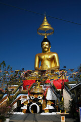 golden buddha statue and flags against blue sky, Pattaya, Thailand