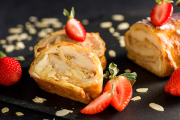 Sliced rolls with custard. The dessert is decorated with fresh strawberries.