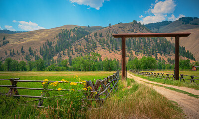 Fototapeta premium Idaho Summer Road Travel Landscape along the Salmon River Scenic Byway U.S. Route 93: The Beautiful Western Rocky Mountains with Wooden Ranch Gate
