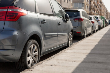 Row of diverse cars parked along urban street, illustrating the typical scene in city parking zone. Ideal for urban planning articles, parking management content, transportation theme illustrations.