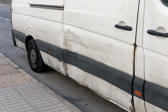 Detailed close-up of a white car with visible damage on its side, featuring dents and scratches. Perfect for showcasing the need for vehicle repairs, insurance case studies, and urban driving risks. - Powered by Adobe