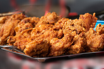 A plate of fried chicken is on a table. The chicken is golden brown and crispy. The plate is on a metal tray