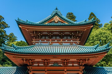 Obraz premium Large Wooden Temple with Green Roof Surrounded by Trees, Symmetrical Composition, Traditional Japanese Architecture, Bright Colors, Tranquil and Grand Scene