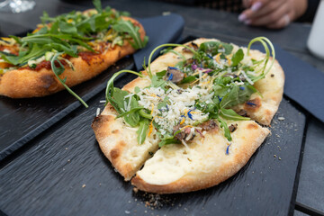 Two mouthwatering pizzas are showcased on a sleek black plate set on a table