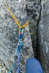 Rappel stance made of loop and cord on a boulder in the mountains. Climber prepared to rappel down.
