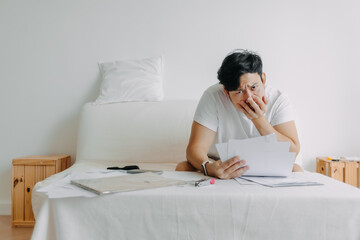 Asian man feeling serious with the paper works and loaning bills account.