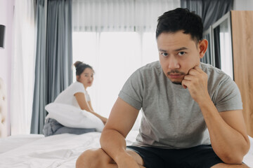 Asian couple lover, husband sad and sulking sit on the bed and wife turning back