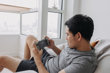 Asian Man concentrate and focus on playing online mobile game in his apartment.