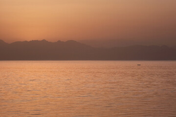 Sunrise view of Gulf of Aqaba of Red Sea with small boat. Dahab, Egypt.