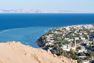 Obraz premium View of Dahab, Red Sea and Saudi Arabia's mountains from viewpoint in the mountains on sunny day, Egypt.