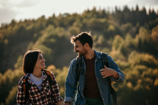 Loving diverse adventure couple holding hands and exploring nature on a beautiful sunny autumn day