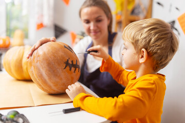 Fototapeta premium Child painting face on pumpkin for Halloween