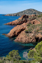 Fototapeta premium Views along Corniche d’Or or Corniche de l’Esterel beautiful coastal road, crystalline blue sea and sky combined with reddish color of Massif de l’Esterel mountains, travel destination in France