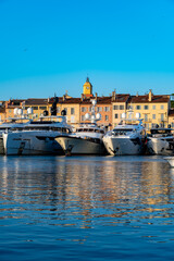 Obraz premium Old port of Saint-Tropez famous touristic village on French Riviera, summer vacation with large yacht boats and colorful houses