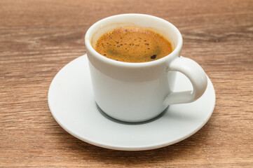 A coffee cup is elegantly placed on a saucer atop a wooden table