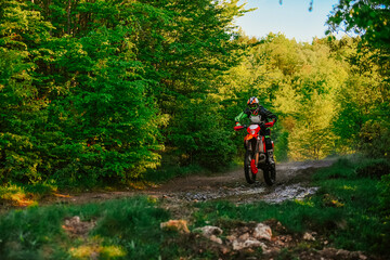 Professional enduro bike rider on action, dirt ride on the muddy road. Motocross sport. 