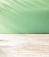 Blurred shadow of  leaves on the light green wall and table top in the foreground. Summer concept.
