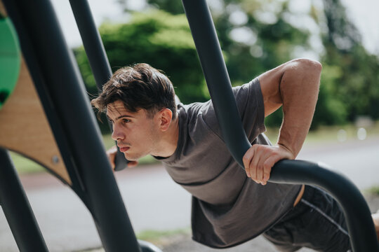 Focused man exercising on parallel bars in an outdoor park. Engaging in fitness routine to build strength and stay healthy.