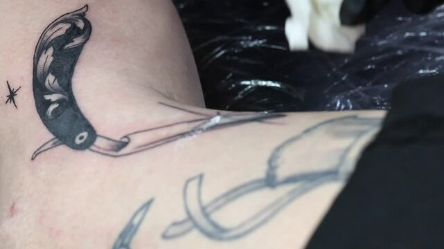 Tatuando detalles en color blanco en dise&ntilde;o de navaja de peluquer&iacute;a