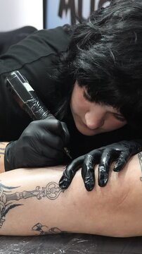Mujer de negocios tatuadora en salon de tatuajes druante el trabajo