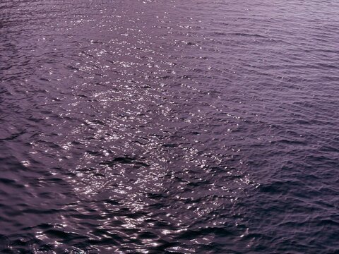 Dark purple glittering ocean water surface rippled background