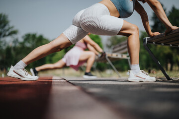 Women stretching in an outdoor park, wearing athletic wear and sneakers. Engaging in fitness and...