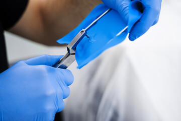Preparing dental dam before installation in mouth by dentist. Doctor applies dental dam to isolate teeth of patient.