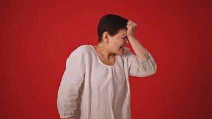 Emotion of Loss and Bewilderment: Mature Woman on Red Background Expressing Despair