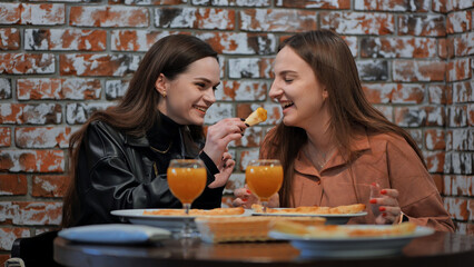 The girls treat each other to slices of pizza.