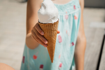 portrait blonde girl in park eating cold ice cream, ice cream melts and runs down the childs hand, summer holiday and fun