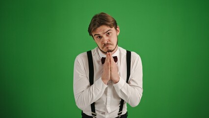 Pleading Young Man with Hands Together on Green Background
