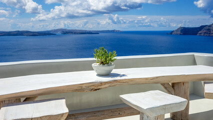 White washed balcony and wooden table with view to the Caldera in Santorini.