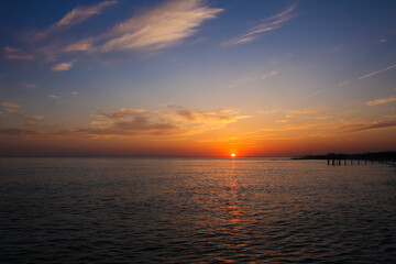 Obraz premium beautiful and colorful sunset, warm light and many clouds, sea waves on the sea coast