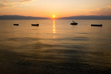 beautiful dramatic landscape of sunset on sea beach with silhouette of boat