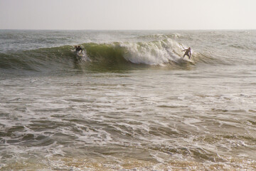 surfers with a board swim on stormy waves in the ocean