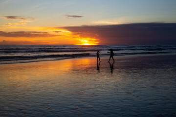 silhouette of children to swim in the sea at sunset