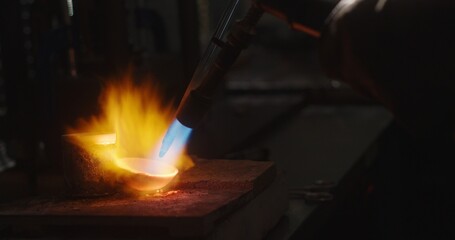 Goldsmith melting gold in crucible with blow torch