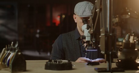 Jeweler Examining Ring Under Warm Lamp Light in Dark Workshop