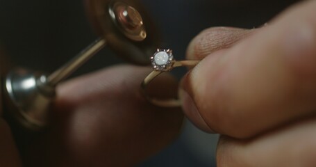Extreme close up - a jeweler polishes a precious stone in a newly created ring