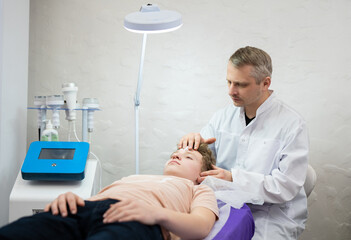 a cosmetologist doctor makes cosmetic procedures on the face of a young guy in a beauty salon
