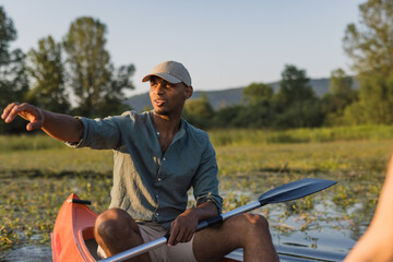 Young man canoeing, paddling, and moving canoe through the lake water, enjoying the natural environment.