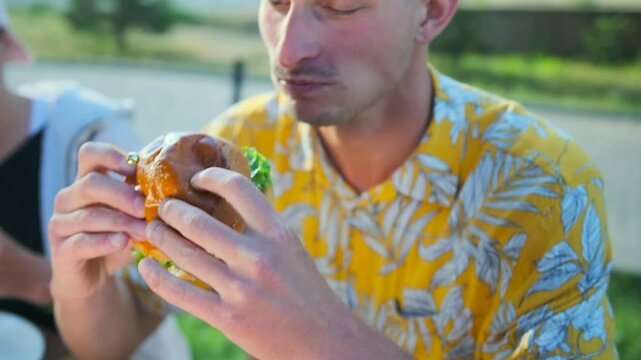 Fresh juicy burger close up in hands hangry man eating junk tasty meal from fast food. Slow motion.