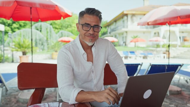 Businessman working on laptop by pool at luxury resort