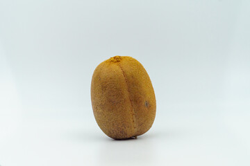 Whole kiwi fruit standing upright on a plain white background, showcasing its brown fuzzy skin. Concept of fresh produce